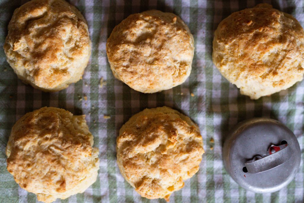 buttermilk biscuits lined up on a gingham towel with a biscuit cutter
