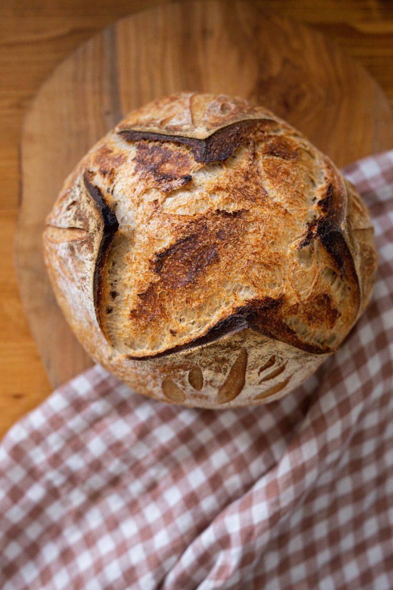 sourdough round loaf resting on gingham towel