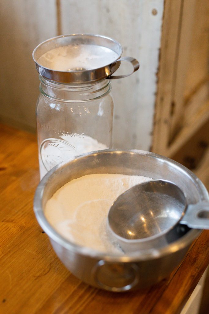 laundry detergent in a bowl next to a mason jar with a funnel