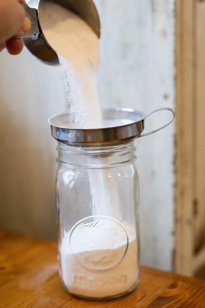 homemade laundry detergent being poured into a mason jar with a funnel