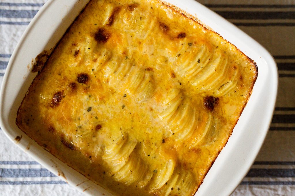 golden baked scalloped potatoes in white pan